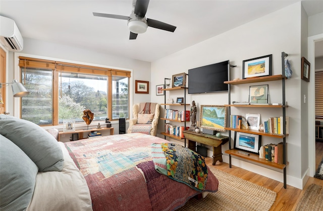 bedroom with ceiling fan, a wall mounted air conditioner, and wood finished floors