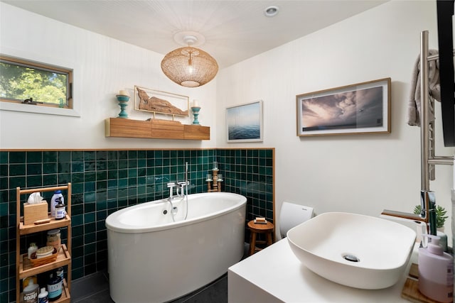 full bathroom with tile walls, wainscoting, a sink, and a freestanding bath