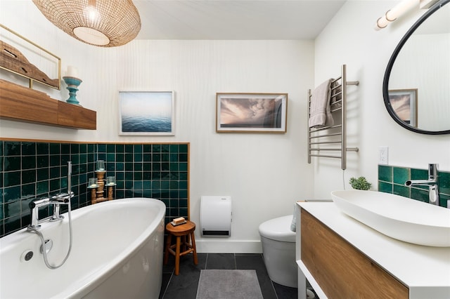 full bath featuring vanity, radiator, a freestanding tub, toilet, and tile patterned floors