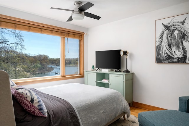 bedroom with ceiling fan, baseboards, and light wood finished floors
