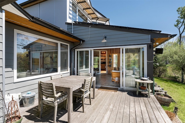 wooden deck featuring outdoor dining space and a sunroom
