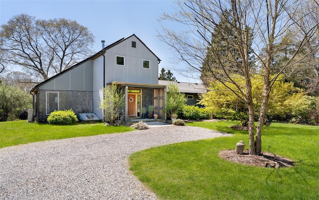 view of front of house with a front lawn, board and batten siding, driveway, and stone siding