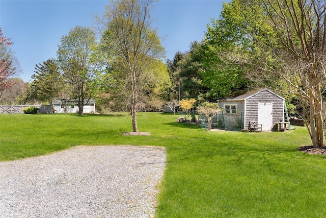 view of yard with an outdoor structure, a shed, and fence
