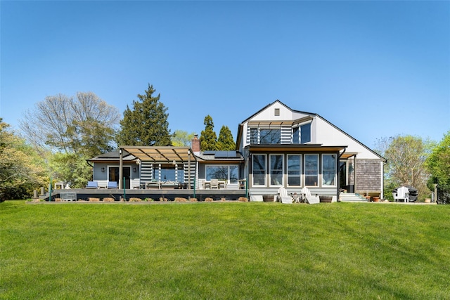 rear view of house with a lawn, a chimney, and solar panels