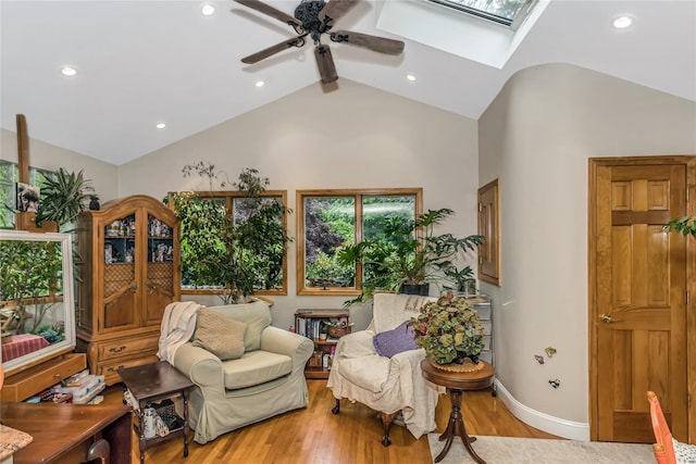 living area with a skylight, recessed lighting, a ceiling fan, baseboards, and light wood-style floors