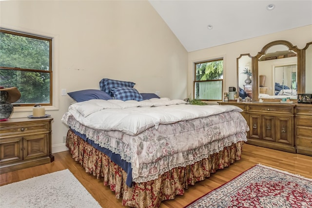 bedroom featuring high vaulted ceiling and wood finished floors