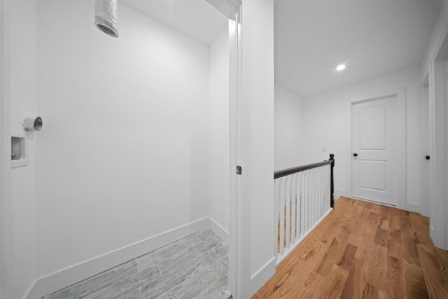corridor featuring baseboards, recessed lighting, light wood finished floors, and an upstairs landing