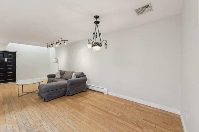 living area with a baseboard radiator, rail lighting, baseboards, light wood-type flooring, and visible vents
