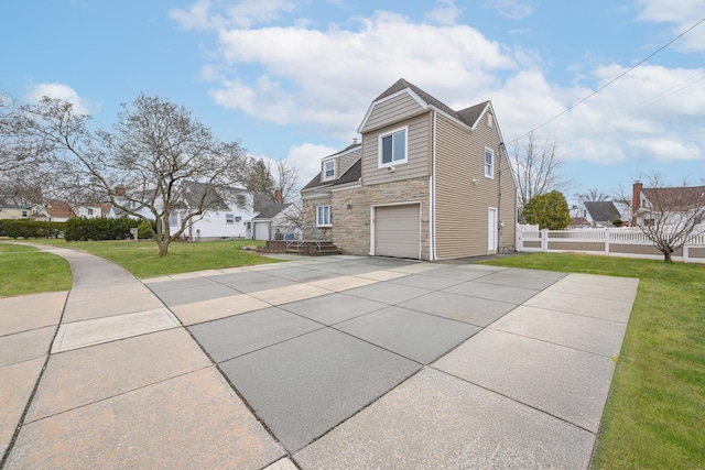 100 Morris Pkwy, Valley Stream, NY 11580 - view of side of home with driveway, a garage, fence, a yard, and stone siding