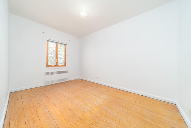 spare room with light wood-style floors, radiator, and baseboards