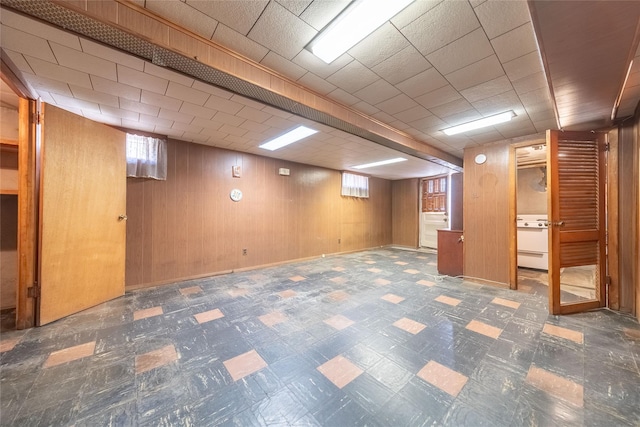 below grade area featuring wooden walls, tile patterned floors, and a healthy amount of sunlight