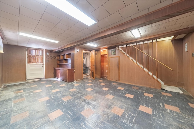 finished below grade area with tile patterned floors, wooden walls, and stairway