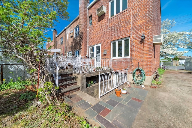 exterior space featuring fence, a wooden deck, and brick siding