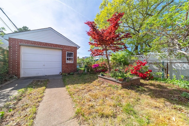 detached garage featuring concrete driveway and fence