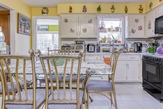 kitchen featuring black appliances, white cabinets, light countertops, tasteful backsplash, and light marble finish flooring
