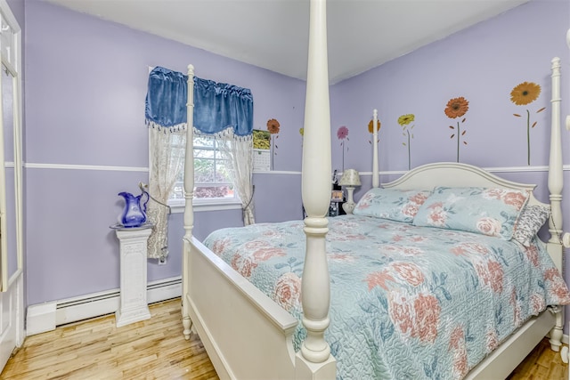 bedroom featuring wood finished floors and a baseboard heating unit