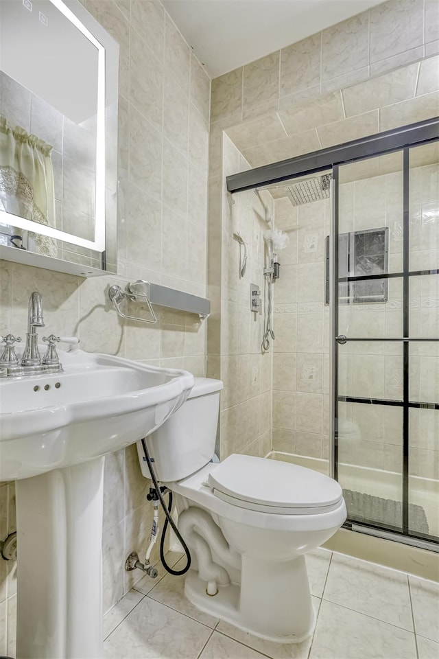full bath with tile walls, toilet, a stall shower, tile patterned flooring, and a sink