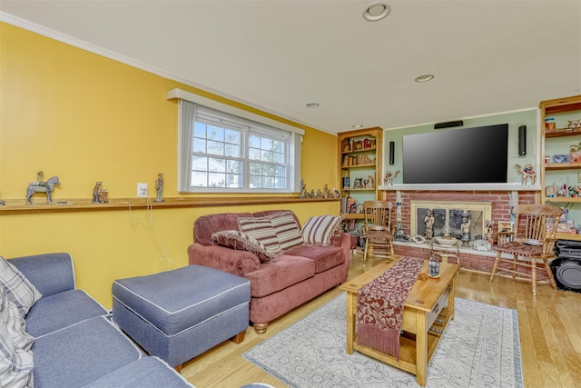 living area featuring wood finished floors, ornamental molding, a brick fireplace, and recessed lighting