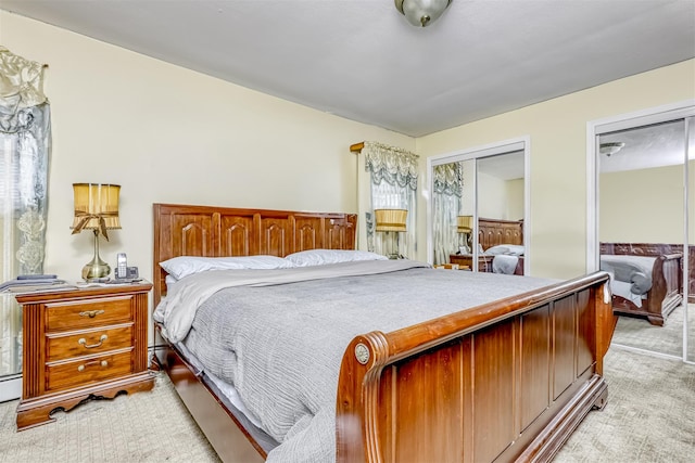 bedroom with light colored carpet and two closets
