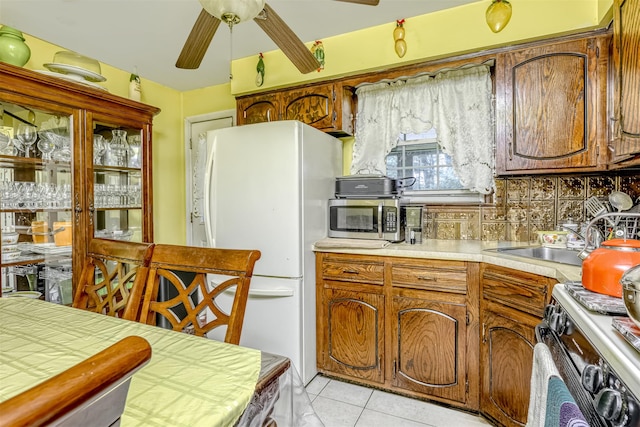 kitchen featuring stainless steel microwave, white refrigerator with ice dispenser, stove, ceiling fan, and a sink