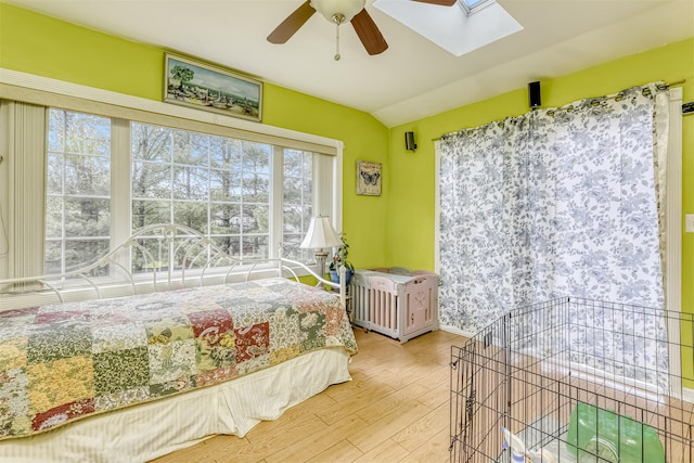 bedroom featuring wood finished floors, a skylight, lofted ceiling, ceiling fan, and baseboards