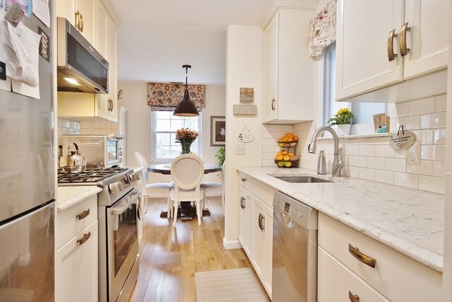 800 Commons Way Unit B, Fishkill, NY 12524 - kitchen featuring appliances with stainless steel finishes, a sink, light wood-type flooring, tasteful backsplash, and light stone countertops