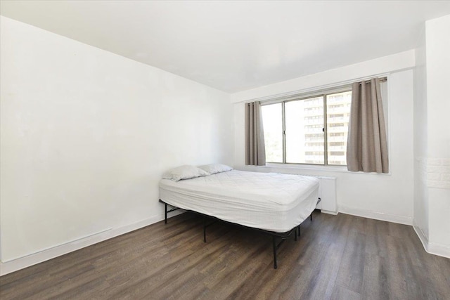 bedroom with dark wood-type flooring and baseboards