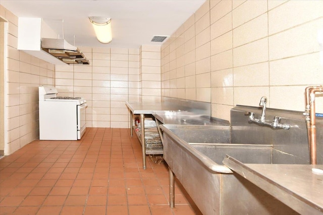 kitchen featuring visible vents, tile patterned flooring, tile walls, white range with gas cooktop, and backsplash