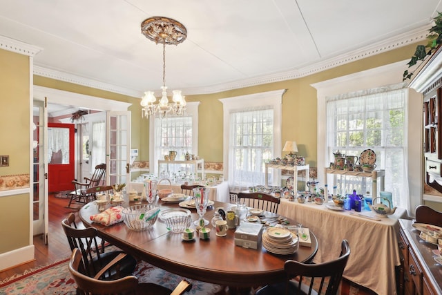dining area featuring an inviting chandelier, ornamental molding, and wood finished floors