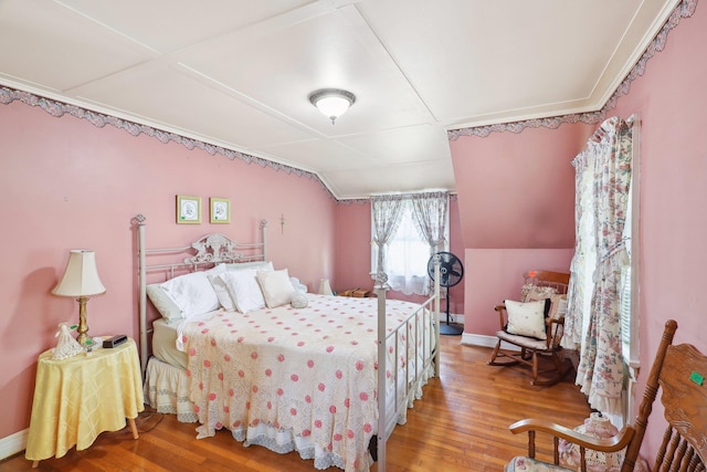 bedroom with crown molding, baseboards, wood finished floors, and lofted ceiling