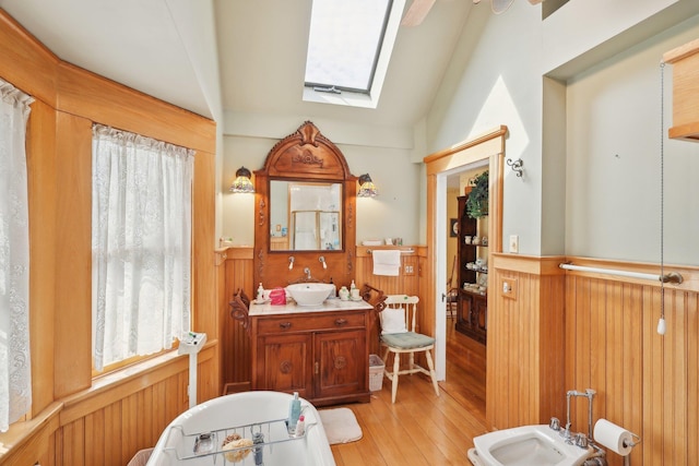 bathroom with a bidet, wood walls, a wainscoted wall, vanity, and hardwood / wood-style floors