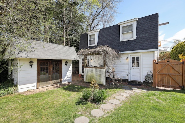 view of front of home with an outdoor structure, a gate, roof with shingles, and a front yard