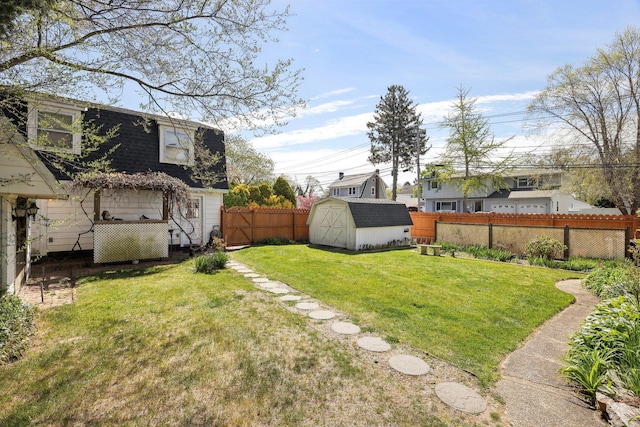 view of yard featuring a fenced backyard, a shed, and an outbuilding