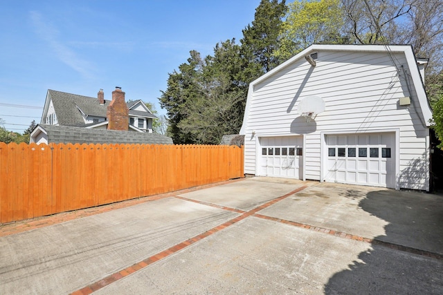 view of side of property with fence, an outbuilding, and a detached garage