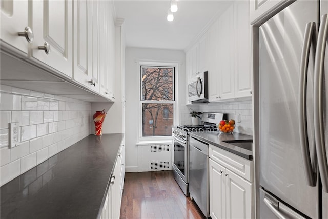 kitchen featuring dark countertops, backsplash, stainless steel appliances, and dark wood finished floors