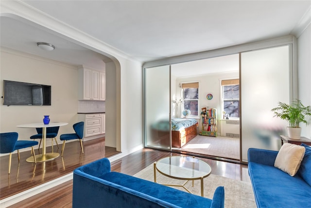 living room with arched walkways, wood finished floors, and radiator
