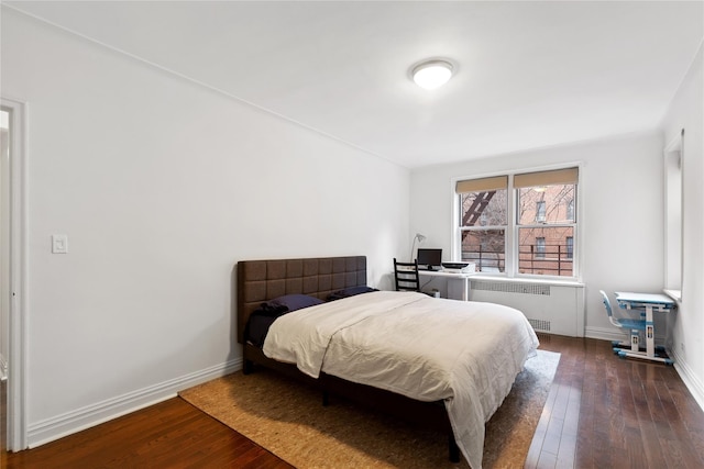 bedroom featuring baseboards, radiator heating unit, and hardwood / wood-style floors