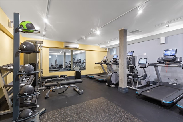 gym with an AC wall unit, visible vents, and track lighting