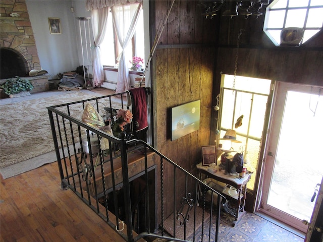 stairway featuring wooden walls, an inviting chandelier, plenty of natural light, and hardwood / wood-style flooring