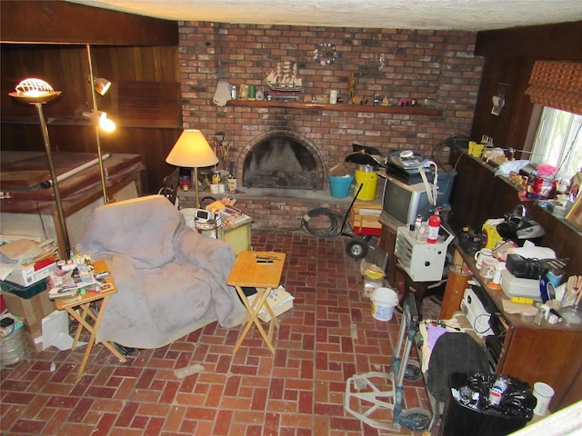 living room featuring wooden walls, brick floor, and a fireplace