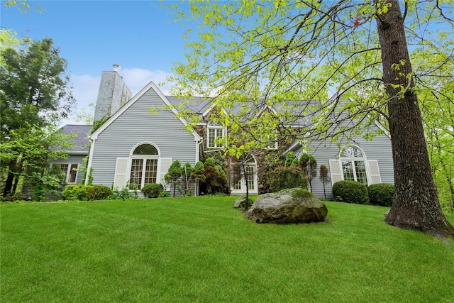 view of front of home with a front lawn, a chimney, and french doors