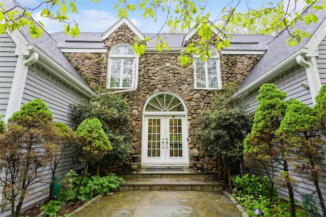 view of exterior entry featuring french doors and stone siding