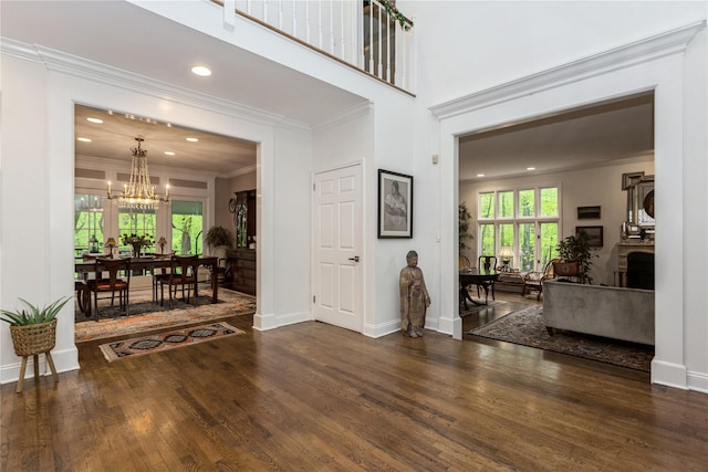 foyer entrance with a chandelier, wood finished floors, ornamental molding, baseboards, and recessed lighting