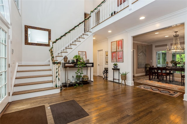 foyer with stairway, a high ceiling, crown molding, wood finished floors, and a chandelier
