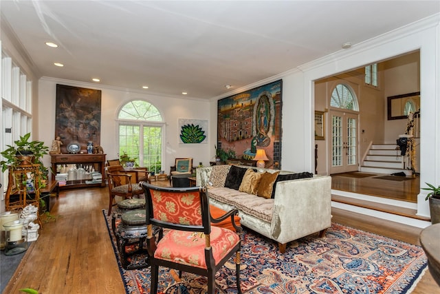 living area with wood finished floors, ornamental molding, recessed lighting, stairs, and french doors