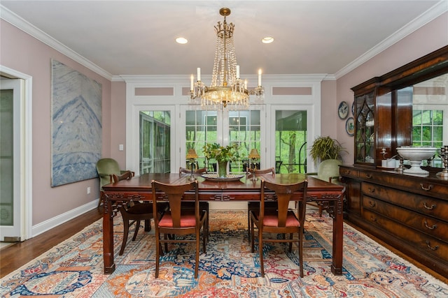 dining area featuring a chandelier, ornamental molding, wood finished floors, and baseboards