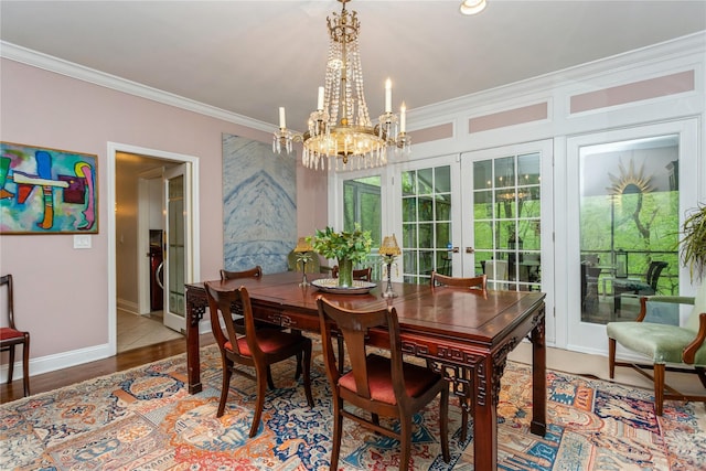 dining area featuring french doors, a chandelier, ornamental molding, plenty of natural light, and baseboards