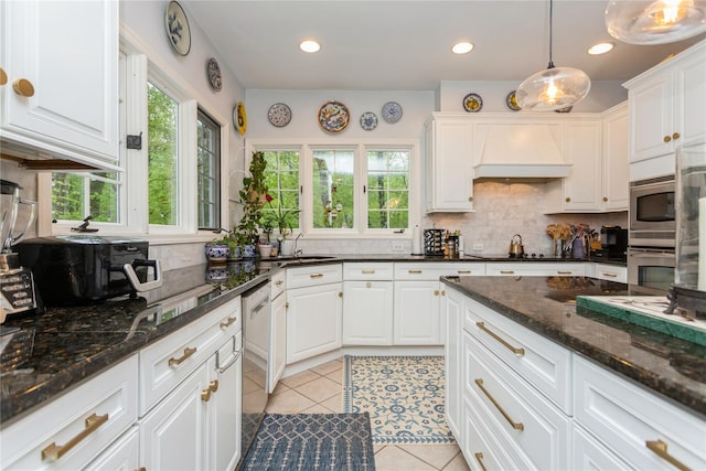 kitchen featuring premium range hood, decorative backsplash, white cabinets, light tile patterned floors, and decorative light fixtures
