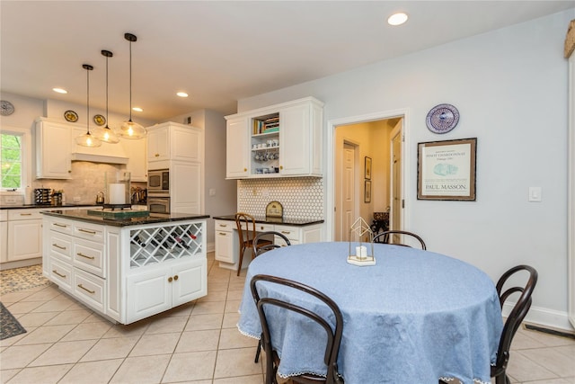 kitchen with dark countertops, appliances with stainless steel finishes, light tile patterned floors, backsplash, and white cabinets