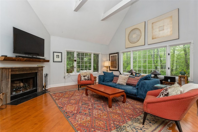 living area featuring high vaulted ceiling, wood finished floors, a fireplace with flush hearth, and baseboards